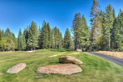 a golf course with rocks on the grass and a road at Bearfoot Lodge Near Fishing and Hiking in Truckee