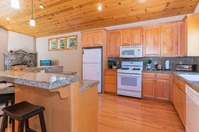 a large kitchen with wooden cabinets and white appliances at Cedar Chateau with Game Room & HOA Access in Truckee