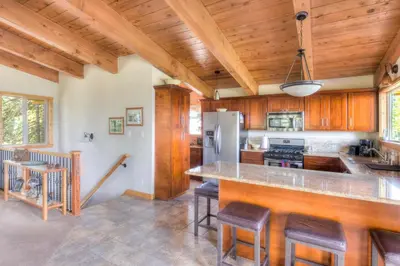 a kitchen with wooden cabinets and a counter with bar stools at Chamberland Getaway Lake Views with Deck in Tahoma