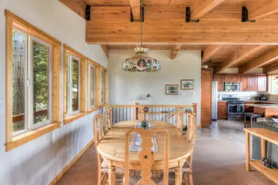 a dining room with a wooden table and windows at Chamberland Getaway Lake Views with Deck in Tahoma