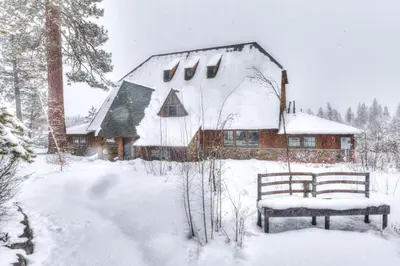 a snow covered house with a bench in front of it at Granlibakken Retreat Near Tahoe Beach in Tahoe City