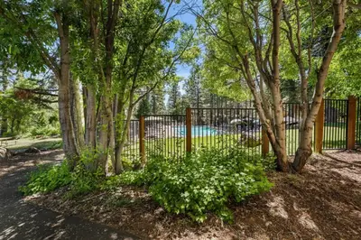 a fence with trees and flowers in front of a pool at Enjoy Forest Views Retreat at Kingswood Village in Kings Beach