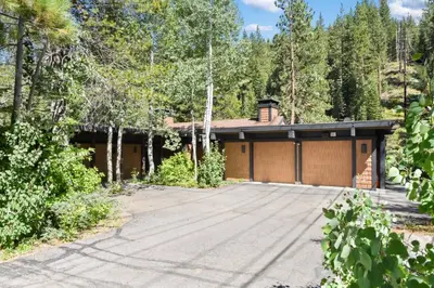 a house with a garage in the woods at Joy on the River Stunning Waterfront Home for 10 in Olympic Valley