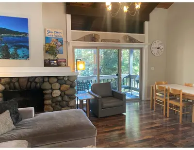 a living room with a couch and a table and a clock at Lake Forest Villa Patio w BBQ in Tahoe City