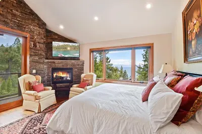 a bedroom with a large bed and a fireplace at Luxury Mountain Chalet Deck w BBQ & Lake Views in Tahoe City
