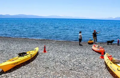 a group of people standing on a beach with three kayaks at Moose Cabin Year Round Outdoor Fun w BBQ in Carnelian Bay