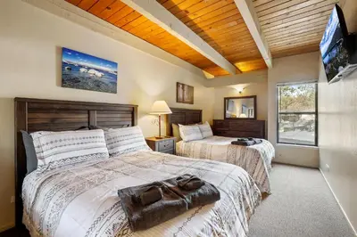 a bedroom with two beds and a flat screen tv at Lakeland Sandy Beach Retreat - Private Escape in South Lake Tahoe
