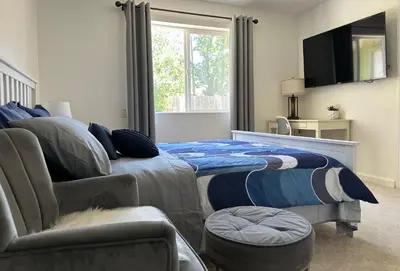 a bedroom with a bed and a chair and a tv at Private Suites in Sacramento