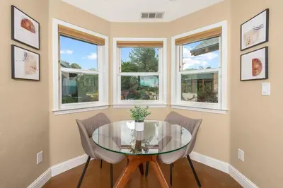 a dining room with a glass table and three windows at Yosemite Cloudline Ridge in Oakhurst