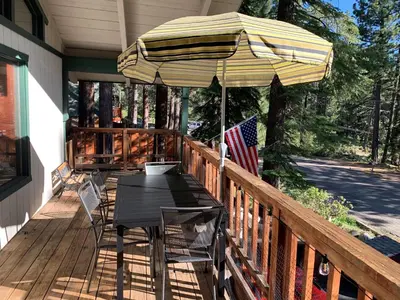 a table with an umbrella on a porch with an american flag at Cherry Hills Cabin - Sleeps 6 No Pets Family Fun in South Lake Tahoe