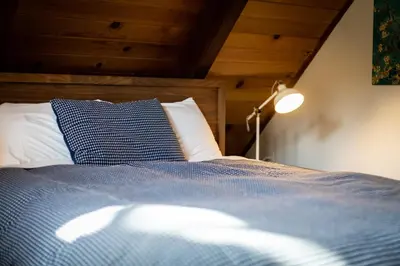 a bedroom with a bed with a blue blanket and a lamp at Christmas Valley Chalet - Tahoe Adventure Awaits in South Lake Tahoe