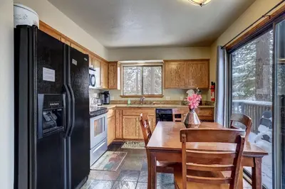 a kitchen with a wooden table and a black refrigerator at Cold Creek Chalet - Hot tub & Movie Room in South Lake Tahoe