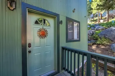 a green house with a blue door and a balcony at Ski In Ski Out 3 BDR Steps from Stagecoach Lift in Stateline