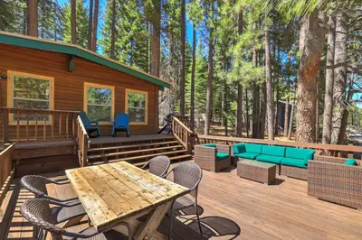 a deck with chairs and tables and a cabin at Shady Pines Pets Hot tub in South Lake Tahoe
