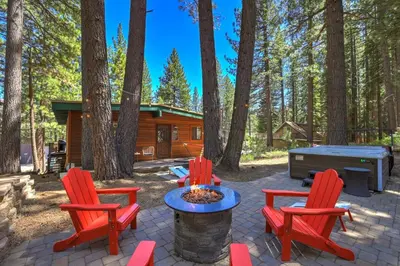 a patio with red chairs and a fire pit and a cabin at Shady Pines Pets Hot tub in South Lake Tahoe