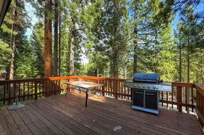 a grill and picnic table on a deck with trees at Nestled Pines Retreat Hot Tub Pool Tahoe Foosball More in South Lake Tahoe