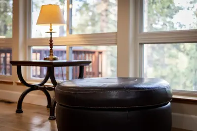 a black ottoman sitting next to a table with a lamp at Nestled Pines Retreat Hot Tub Pool Tahoe Foosball More in South Lake Tahoe