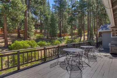 a patio with tables and chairs on a deck with trees at Prima Del Norte - Hot tub Pool Table Arcade Game in South Lake Tahoe