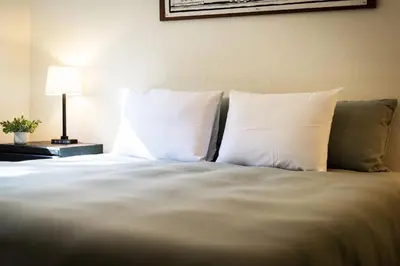 a bed with white pillows and a table with a lamp at Rustic Haven - Hot tub & Pet friendly in South Lake Tahoe