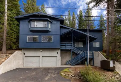 a blue house with a garage in the woods at Southern Pines Arcade Games & Foosball for Kids in South Lake Tahoe
