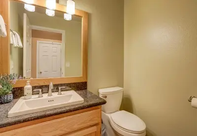 a bathroom with a toilet and a sink and a mirror at Sutter Trail Sparkles - Air conditioned large family home in South Lake Tahoe
