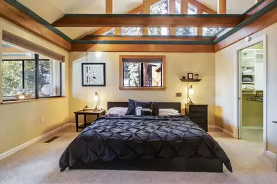 a bedroom with a large bed and windows at Mountainside Overlook Lake Views & Hot Tub in Kings Beach