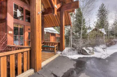 a wooden cabin with a porch in the snow at Luxury Northstar Palace with Hot Tub & Games in Truckee