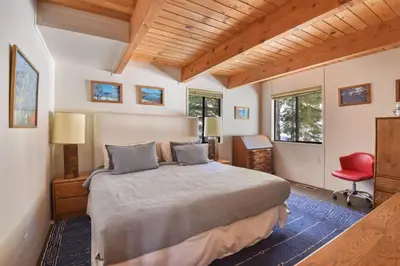 a bedroom with a large bed and a red chair at Northstar Treehouse Chic 4BR House Forest view in Truckee