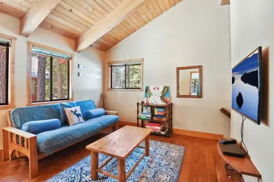 a living room with a blue couch and a table at Northstar Treehouse Chic 4BR House Forest view in Truckee