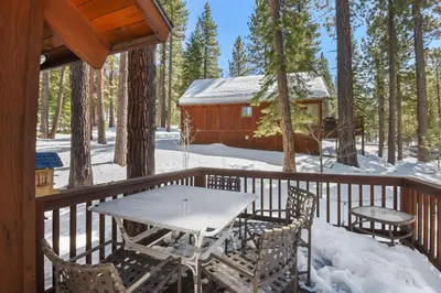 a table and chairs on a deck in the snow at Northstar Treehouse Chic 4BR House Forest view in Truckee