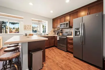 a kitchen with stainless steel appliances and wooden cabinets at Powder Run Retreat Modern Stay for 6 With On-site Ski Access & Mountain Views in Truckee