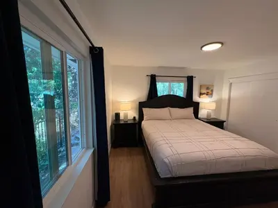 a bedroom with a bed and two windows at Downtown-Pool,Firepit,Trees, WFH-No gate fee like PML in Groveland