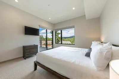 a bedroom with a large white bed and a window at Village Walk 7470 by East West Hospitality in Truckee