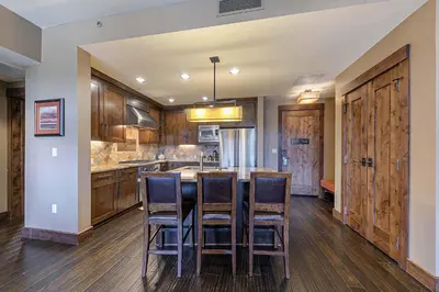 a kitchen with wooden cabinets and a island with bar stools at Northstar Lodge 306 by East West Hospitality in Truckee