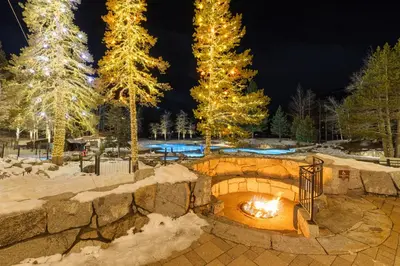 a fire pit in a snow covered yard with christmas trees at Everline Resort & Spa Palisades- Forest View in Olympic Valley