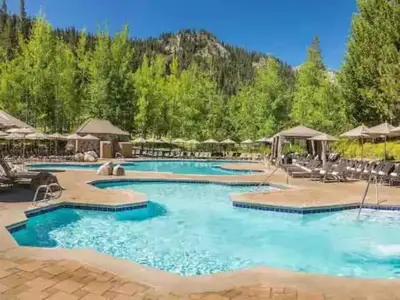 a pool at a resort with chairs and umbrellas at Everline Resort & Spa Palisades- Forest View in Olympic Valley