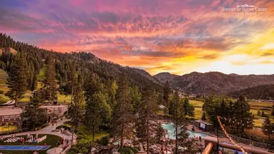 a sunset over a resort with a river and trees at Everline Resort & Spa Palisades-Valley View Suite in Olympic Valley
