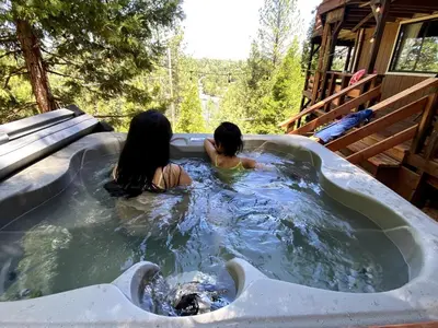 two people in a jacuzzi tub in a cabin at Private Lakeview Yosemite Full House El Capitan with Panoramic Sauna, Seasonal HotTub, WiFi in Groveland