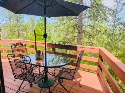 a table and chairs on a deck with an umbrella at Private Lakeview Yosemite Full House El Capitan with Panoramic Sauna, Seasonal HotTub, WiFi in Groveland