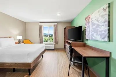 a hotel room with a bed and a desk and a television at ECHO Suites Extended Stay by Wyndham Reno in Reno