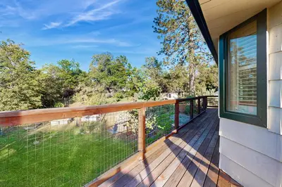a balcony with a view of the woods at Deer Paradise in Coarsegold