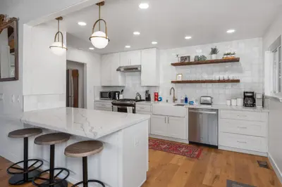 a kitchen with white cabinets and a large island with stools at Yosemite Family Ranch in Oakhurst