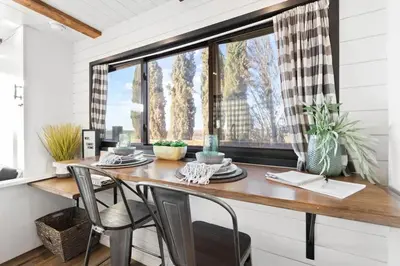a dining room with a table and chairs and a window at Rooftop Spa Tiny Cargo Home Farm Experience in Tulare