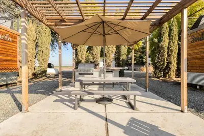 a picnic table with an umbrella on a patio at Rooftop Spa Tiny Cargo Home Farm Experience in Tulare