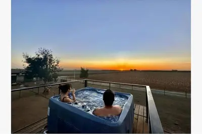 two people in a hot tub watching the sunset at Rooftop Spa Tiny Cargo Home Farm Experience in Tulare