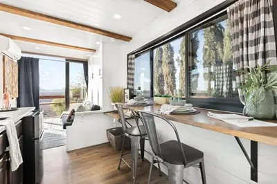 a kitchen with a counter with chairs and a large window at Rooftop Spa Tiny Cargo Home Farm Experience in Tulare