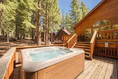 a hot tub on a deck next to a cabin at Jackpine Lodge at Tahoe Donner by Tahoe Getaways - Private Hot Tub w Foosball and HOA in Truckee