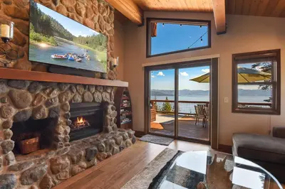 a living room with a stone fireplace and a tv at Shoreline Vista - Lake Views Near Hike & Bike in Carnelian Bay