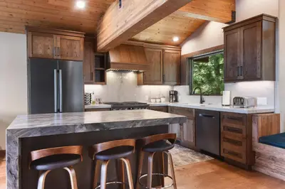 a kitchen with wooden cabinets and a large island with bar stools at Shoreline Vista - Lake Views Near Hike & Bike in Carnelian Bay