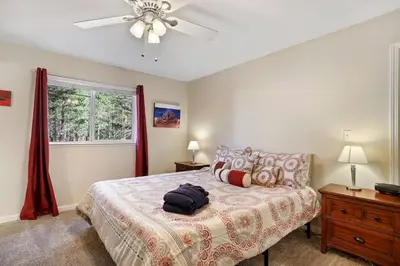 a bedroom with a bed with a ceiling fan and a window at Tahoe Frost - Air conditioned 4 bedroom Tahoe home in South Lake Tahoe